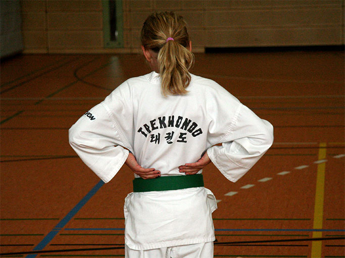 Mädchen von hinten mit Tobok und Taekwondo-Schriftzug und Grüngurt